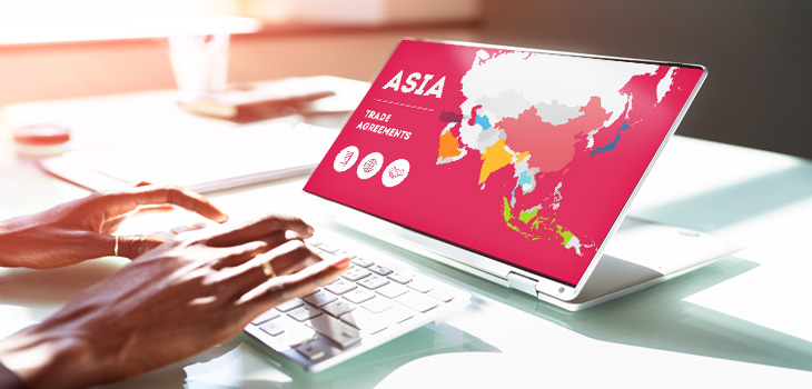 Photo des mains d’une personne touchant le clavier d’un ordinateur portable montrant une illustration d’une carte de l’Asie