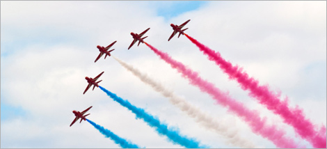 Photo d'un spectacle aérien : cinq avions libérant des jets de fumé colorés.
