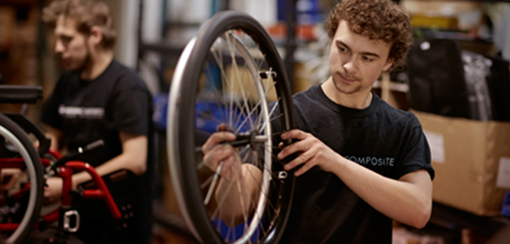 Photo d'un employé fabriquant une roue de fauteuil roulant.  Photo prise dans l'atelier de Motion Composites.