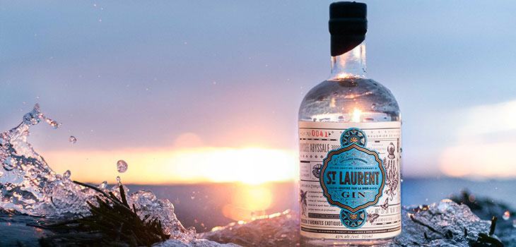 Photo d'une bouteille de gin St. Laurent sur un rocher sur les rives du fleuve
