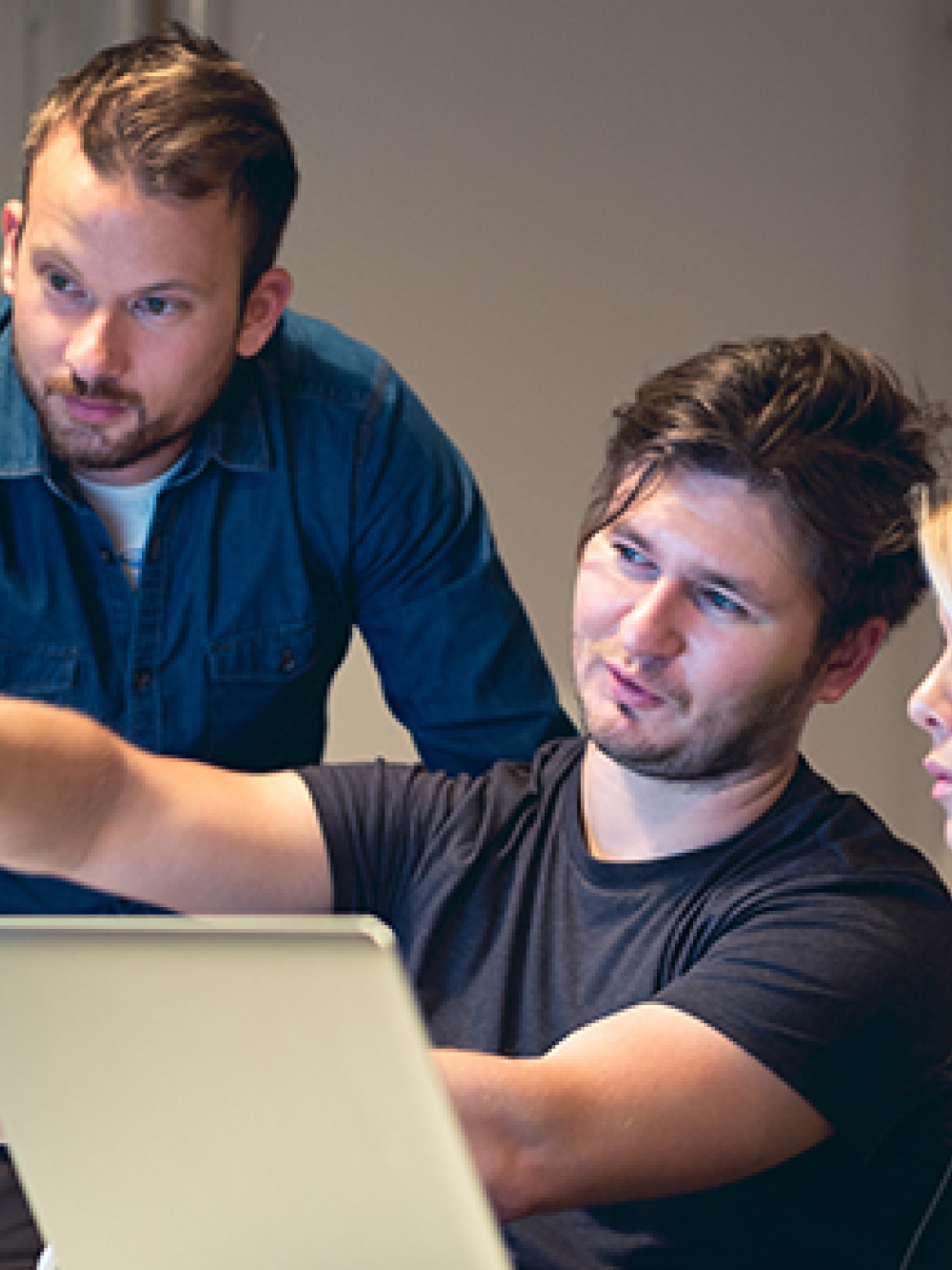 Groupe de personnes travaillant ensemble devant des écrans d’ordinateur dans un environnement de bureau. 