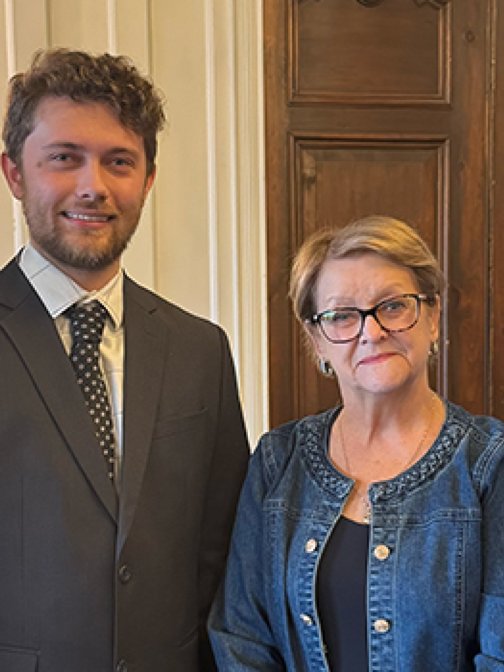 Quatre personnes debout à l’intérieur d’une salle officielle.