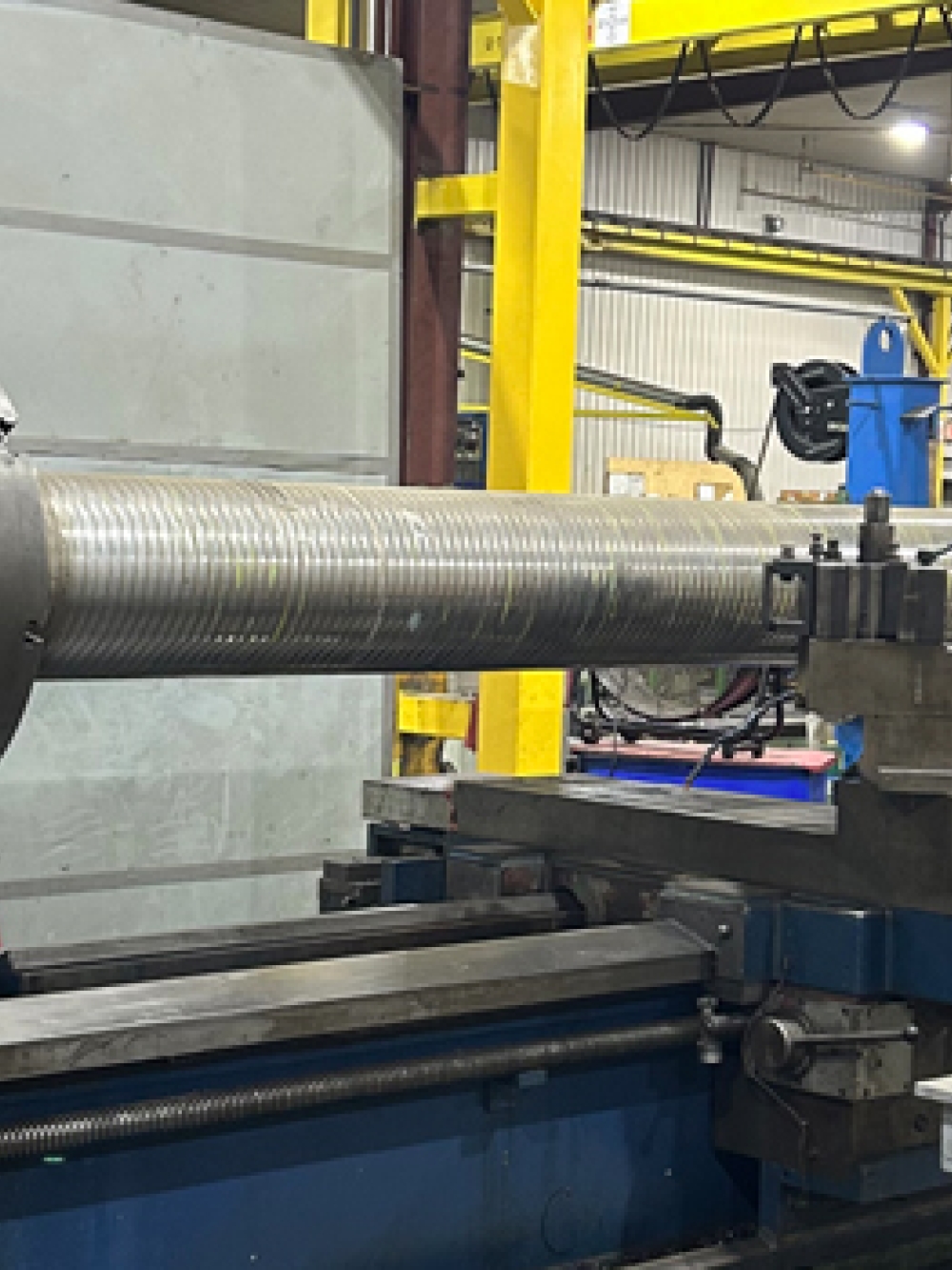 Grande machine industrielle MT 700 en atelier, équipée d’un long cylindre métallique fixé pour l’usinage, avec des structures et équipements d’usine en arrière‑plan.