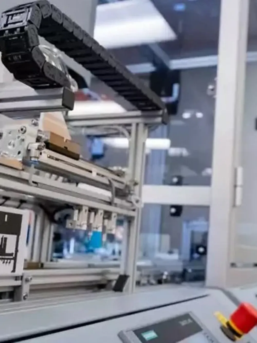 Équipement automatisé de laboratoire avec un système robotisé et des rails mécaniques, contrôlé depuis un panneau de commande industriel dans un environnement technique fermé.