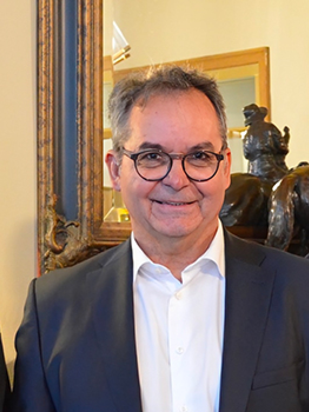 Trois personnes en tenue professionnelle posant à l’intérieur, devant un miroir et une sculpture décorative.