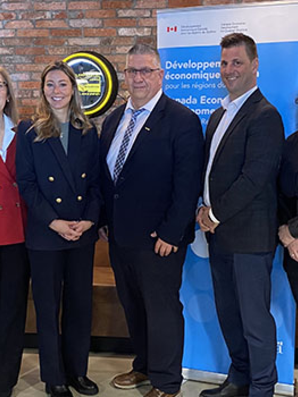 Groupe de sept personnes posant à l’intérieur devant des drapeaux, des bannières gouvernementales.