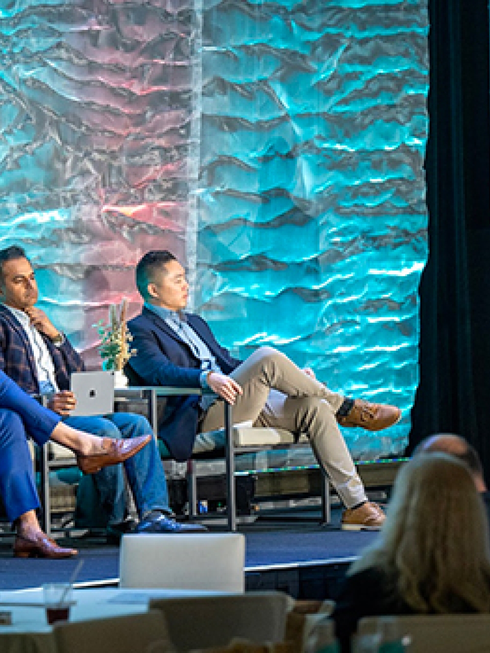 Présentation lors d’une conférence, avec une personne debout à un podium devant un écran affichant des images de cuir chevelu, et plusieurs personnes assises sur scène.