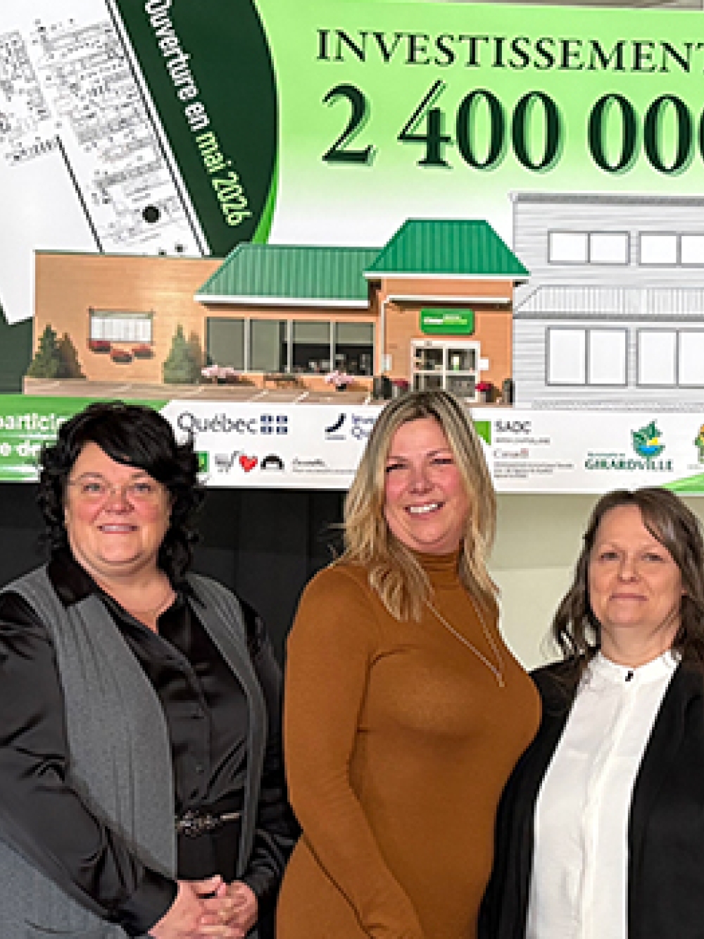Cinq personnes posent devant un panneau annonçant un investissement de 2 400 000 $ pour un projet immobilier, accompagné d’un dessin architectural et de logos de partenaires. 
