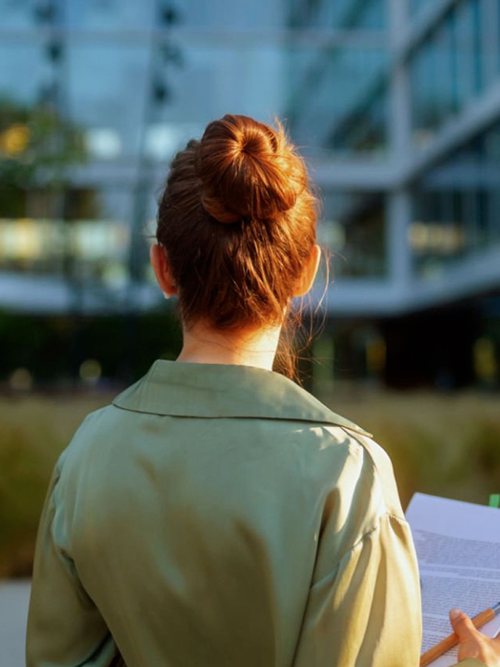 Une femme tenant un calepin de notes regarde l'extérieur d'une entreprise
