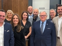 Groupe de personnes debout dans un espace intérieur aménagé, comprenant des armoires et un comptoir, posant pour une photo de groupe.