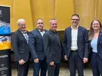 Groupe de personnes debout dans un atelier industriel, posant près d’une bannière d’ASDR et d’un drapeau du Québec.