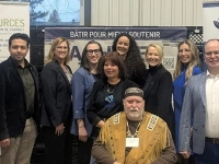 Groupe de personnes réunies devant des bannières d’Aux Sources du Bassin de Chambly, dans un espace intérieur, dont l’une est assise au premier plan.