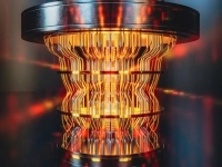 Représentation stylisée d’un ordinateur quantique cylindrique aux parois lumineuses orangées, avec des circuits verticaux lumineux et une structure métallique sombre en haut et en bas.