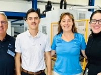 Quatre personnes debout dans un atelier industriel, posant devant de l’équipement de machinerie.