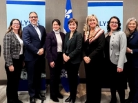Groupe de personnes debout dans une salle de conférence devant deux panneaux ELYSIS et un drapeau du Québec, posant pour une photo officielle.