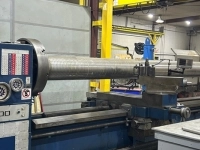 Grande machine industrielle MT 700 en atelier, équipée d’un long cylindre métallique fixé pour l’usinage, avec des structures et équipements d’usine en arrière‑plan.