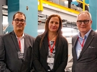 Trois personnes en tenue professionnelle posant devant la nouvelle ligne de tri d’Estrie Aide, avec les équipements industriels visibles en arrière‑plan.