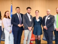 Groupe de personnes debout dans une salle de conférence, posant devant deux bannières d’Investissement Québec et un drapeau du Québec.