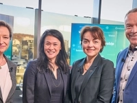 Groupe de personnes en tenue professionnelle posant devant des écrans.