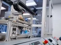 Équipement automatisé de laboratoire avec un système robotisé et des rails mécaniques, contrôlé depuis un panneau de commande industriel dans un environnement technique fermé.