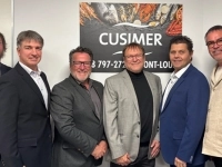 Groupe de six personnes debout dans un local, posant devant une affiche de l’entreprise Cusimer.