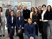 Groupe de personnes réunies dans un laboratoire laissant voir du matériel scientifique en arrière‑plan.