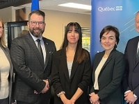 Groupe de cinq personnes posant à l’intérieur devant des fenêtres exposées et une bannière du gouvernement du Québec.