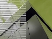 Vue artistique d’un bâtiment moderne en revêtement métallique, avec des lignes diagonales et un ciel vert en arrière‑plan.