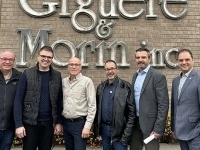 Groupe de personnes debout devant la façade en brique de l’entreprise Giguère & Morin inc., posant pour une photo à l’extérieur du bâtiment.