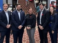 Groupe de personnes posant dans un hall d’événement, entouré de bannières promotionnelles et de participants, lors d’une activité officielle.