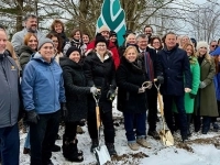 Grand groupe de personnes rassemblées à l’extérieur en hiver, tenant des pelles dorées pour une cérémonie de première pelletée de terre, devant un drapeau associé à la Fondation Gisèle-Faubert.