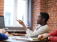 Trois personnes sont réunies autour d’une table dans un espace de travail en briques, discutant devant un écran d’ordinateur affichant du code.