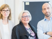 Trois personnes posent dans un environnement de laboratoire lumineux, devant du matériel scientifique.