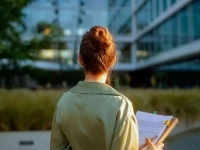 Une femme tenant un calepin de notes regarde l'extérieur d'une entreprise