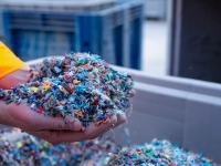 Main montrant une pile de copeaux de plastique dans un centre de tri