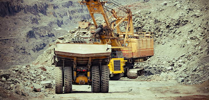 Photo d’un camion lourd et d’une excavatrice dans une mine de fer à ciel ouvert